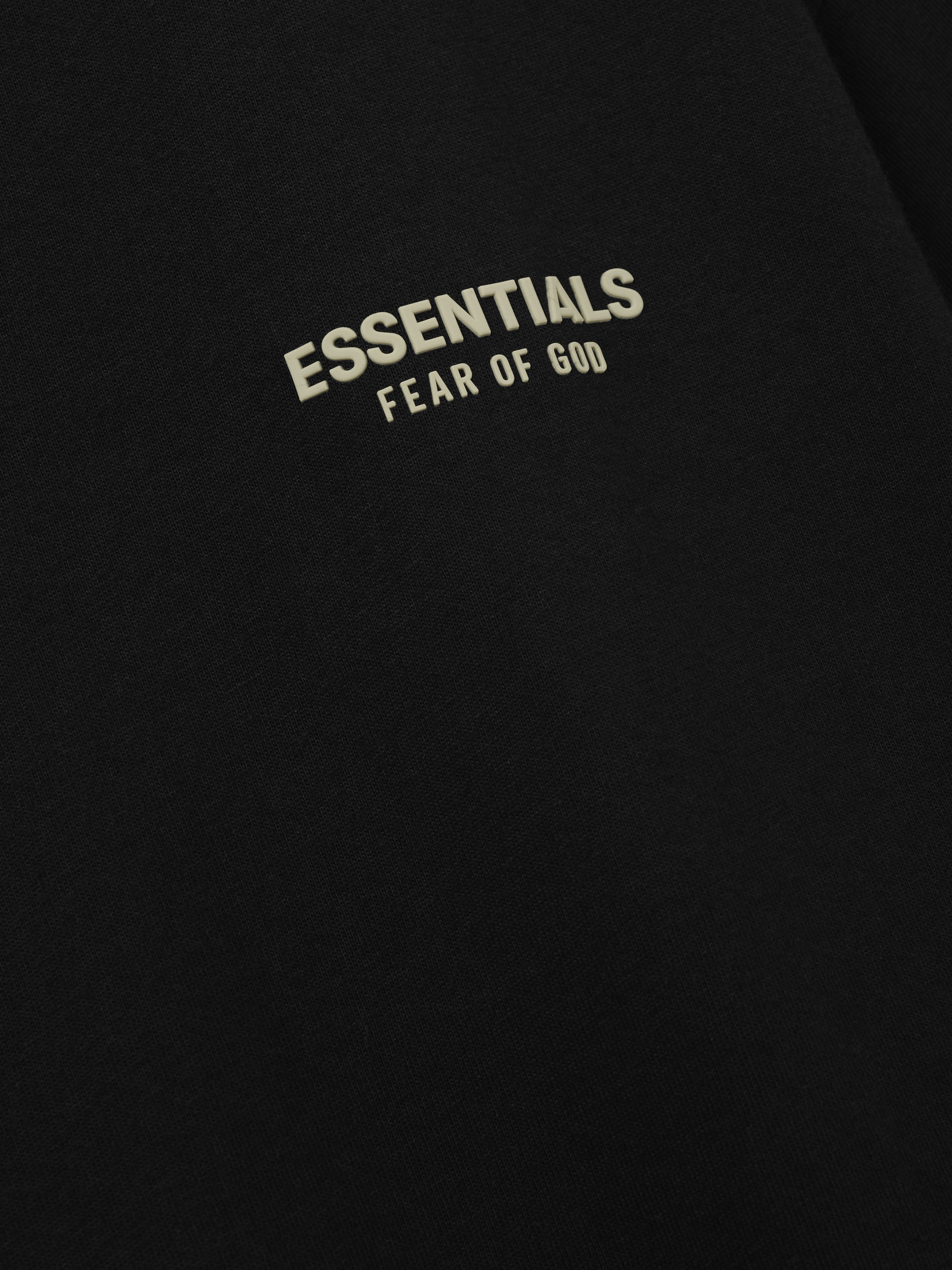 Essentials FW26 Classic Tee close up of black fabric featuring a cream Essentials Fear of God logo detail with soft texture Tops
