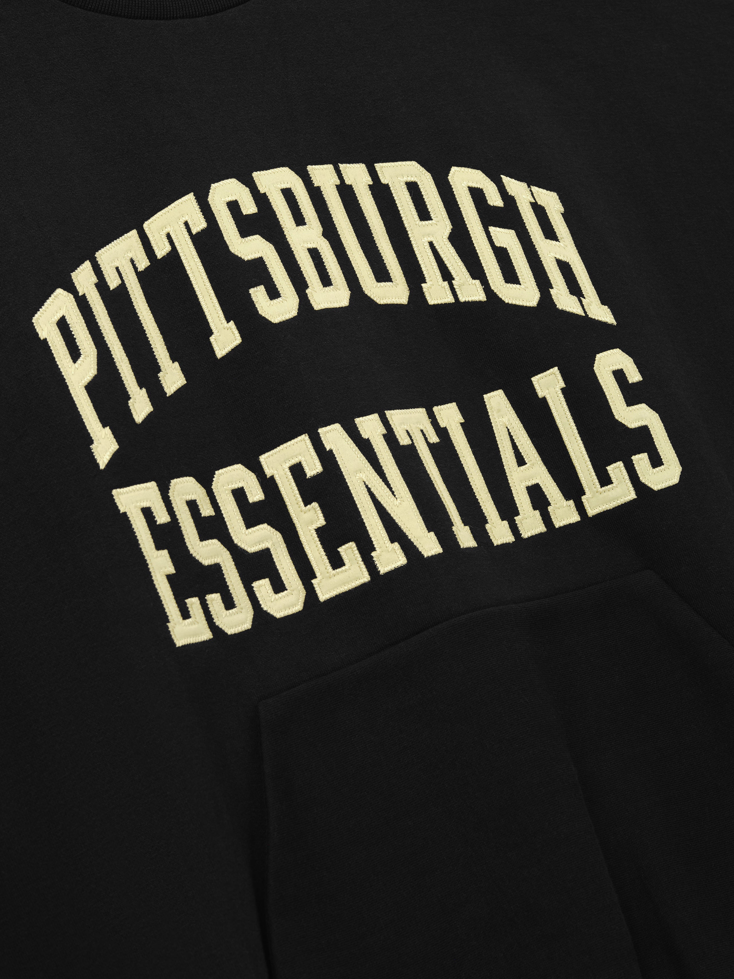 Steelers 90s Relaxed Crewneck black sweatshirt featuring cream Pittsburgh Essentials collegiate lettering and kangaroo pocket shown as a Tops product detail