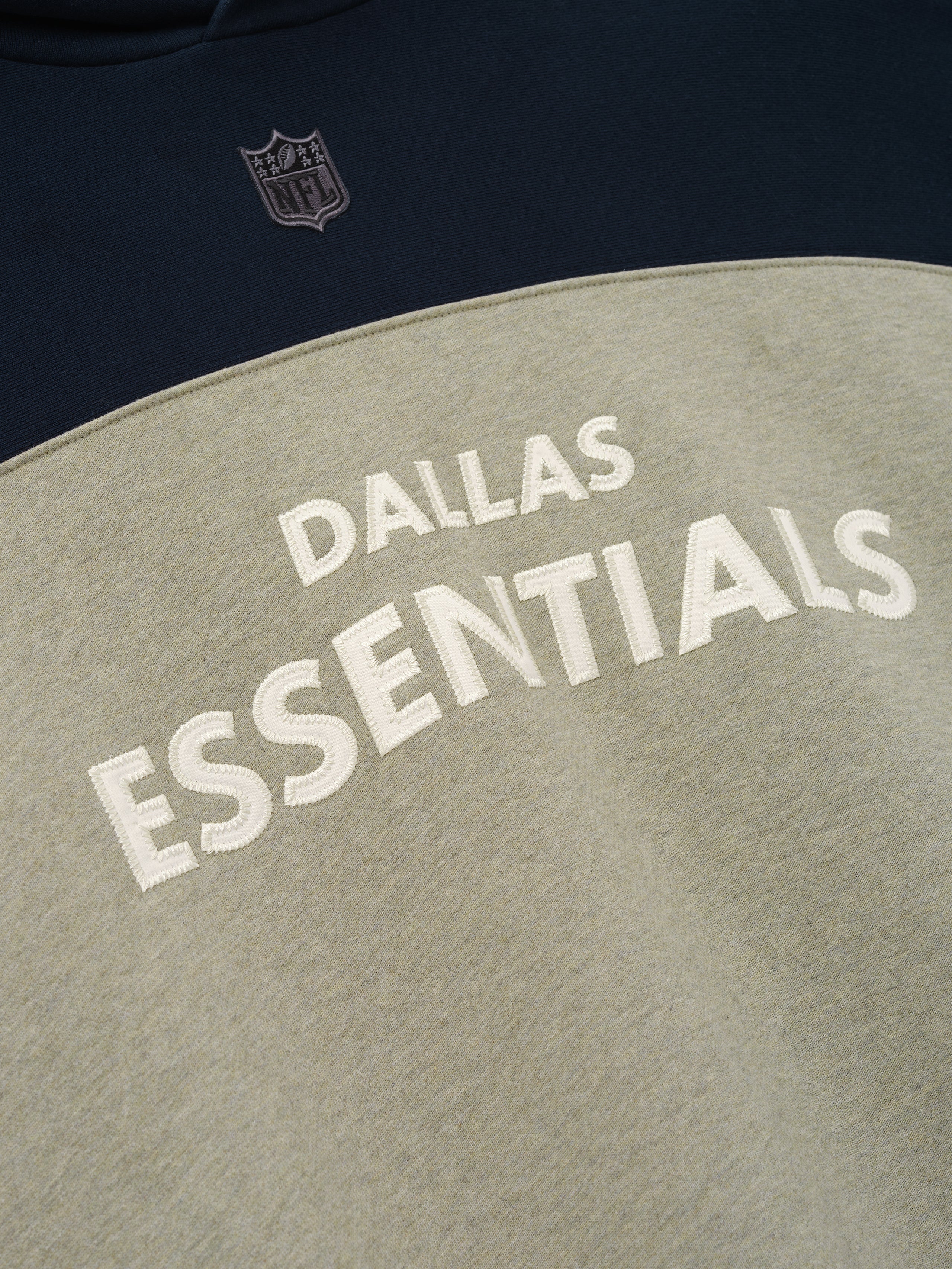 Cowboys 90s Relaxed Hoodie navy and stone color block close up with embroidered NFL shield and Dallas Essentials lettering shown as a Tops product detail