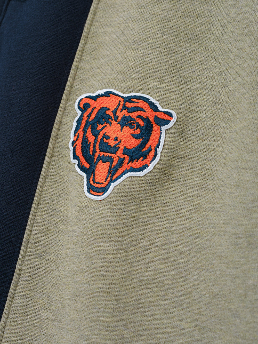 Bears Lounge Sweatpant close up showing an embroidered bear emblem on taupe fleece beside a navy side panel as a Bottoms product detail