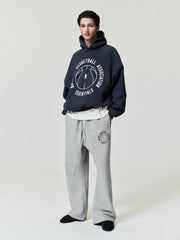 navy oversized hoodie with circular NBA Essentials text and basketball graphic worn with gray sweatpants with matching logo
